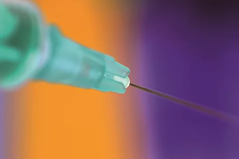 Spritze mit gelb lila Hintergrund