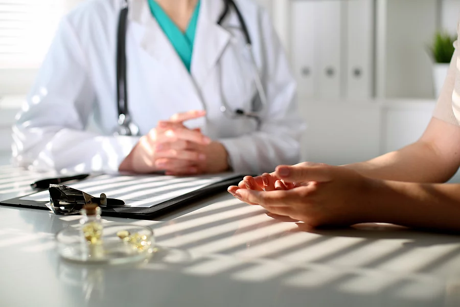 Arzt und Patient sitzen an einem Tisch in der Praxis.
