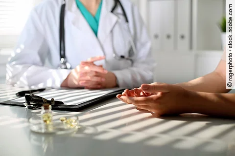 Arzt und Patient sitzen an einem Tisch in der Praxis.