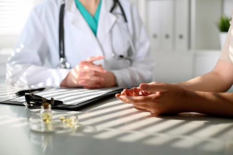 Arzt und Patient sitzen an einem Tisch in der Praxis.