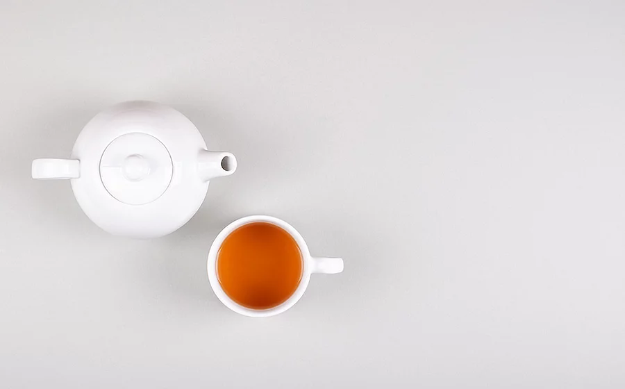 Weiße Teekanne mit Tasse, gefüllt mit Tee