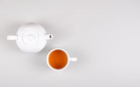 Weiße Teekanne mit Tasse, gefüllt mit Tee