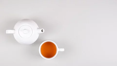 Weiße Teekanne mit Tasse, gefüllt mit Tee