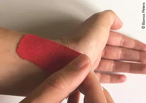 Hand mit rotem Tape.