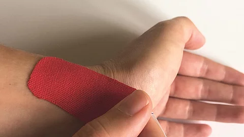 Hand mit rotem Tape.