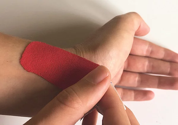 Hand mit rotem Tape.