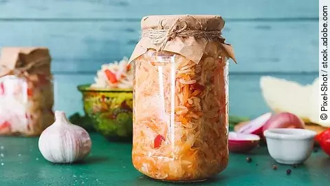 Fermentierte Lebensmittel, im Fokus ein Glas mit eingelegtem Kraut