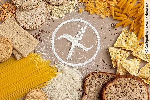 verschiedene Getreide und Brot liegen auf einem Tisch, in der Mitte ein Glutenfrei-Zeichen aus Mehl