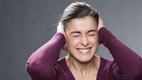 Junge Frau hält sich die Ohren zu aufgrund von Lautstärke