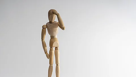 Holzpuppe hält sich die Hand an den Kopf.
