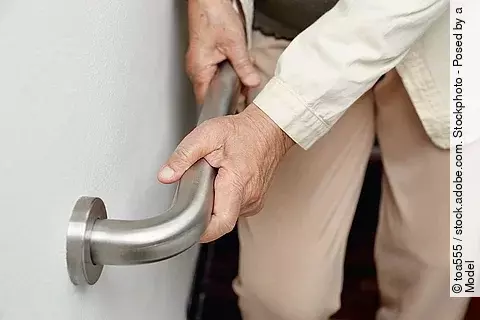 Alte Frau hält sich an einer Türklinke fest