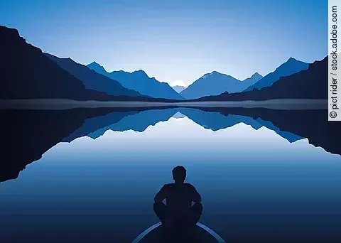 Mann sitzt auf Bootssteg am See von Bergen umgeben