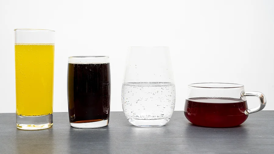 4 Gläser nebeneinander: Limo, Cola, Wasser, Früchtetee