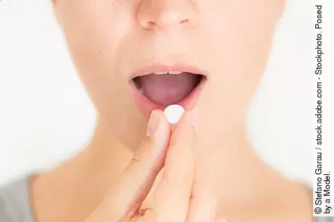 Junge Frau nimmt eine weiße Pille ein