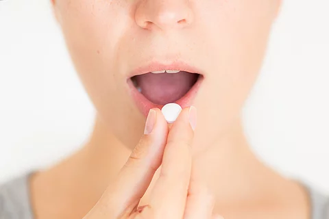 Junge Frau nimmt eine weiße Pille ein