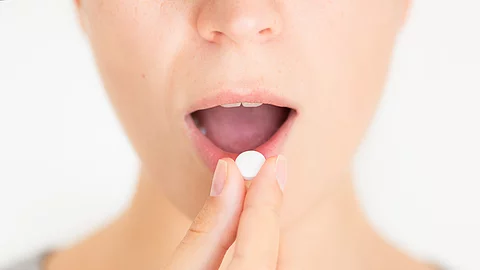 Junge Frau nimmt eine weiße Pille ein
