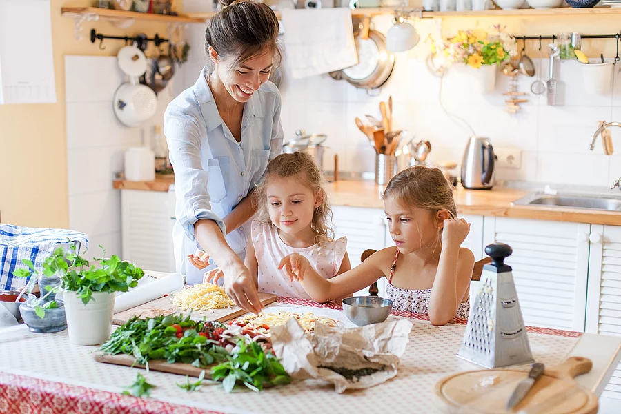 Mutter und 2 Kinder bereiten gemeinsam Pizza zu