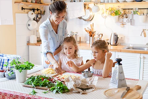 Mutter und 2 Kinder bereiten gemeinsam Pizza zu