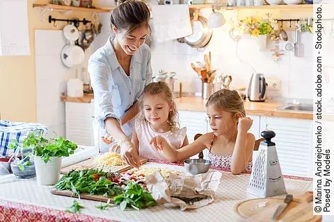Mutter und 2 Kinder bereiten gemeinsam Pizza zu