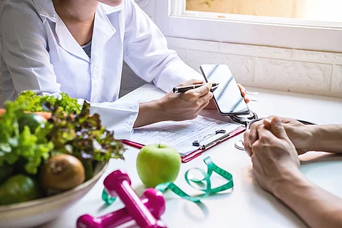 Ernährungsberaterin am Tisch mit Obst und Gemüse und Handy
