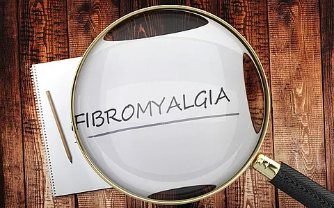 Zettel mit Schriftzug Fibromyalgie unter einer Lupe