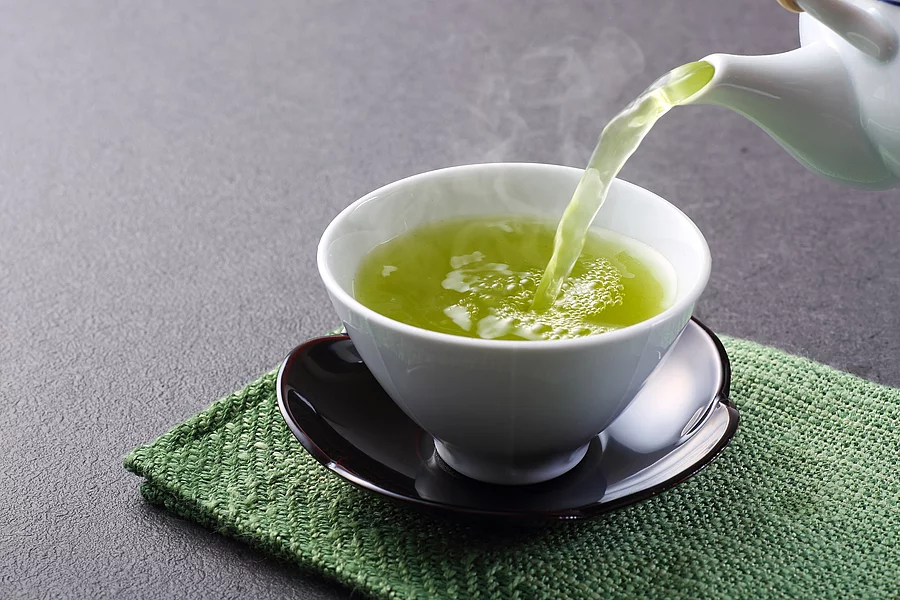 Teekanne und Teetasse mit grünem Tee