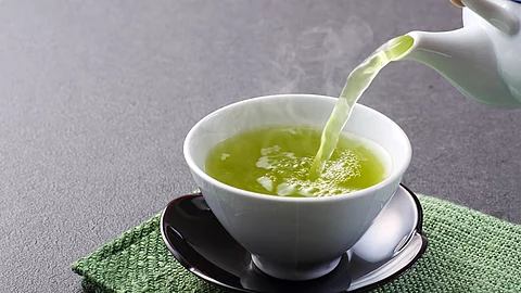 Teekanne und Teetasse mit grünem Tee