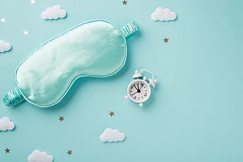 Schlafmaske, Wölkchen und ein Wecker auf türkisem Hintergrund