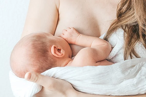 Frau, die ihr Baby auf dem Arm hält und stillt.