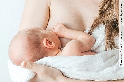 Frau, die ihr Baby auf dem Arm hält und stillt.