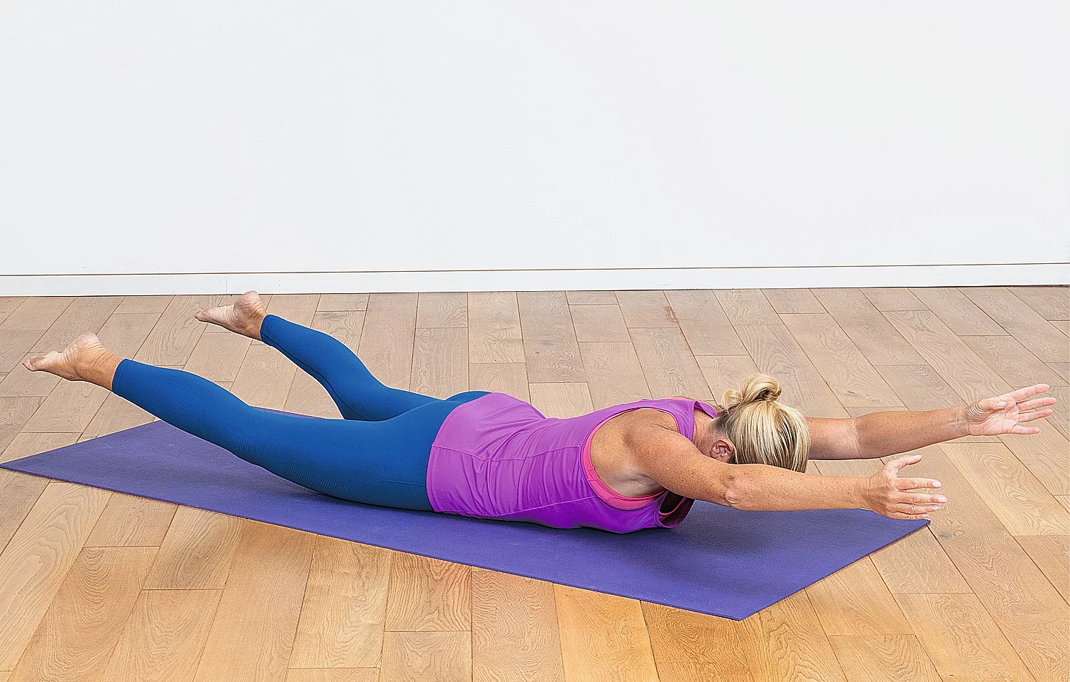Blonde Frau macht Kraftübung auf einer Yoga-Matte.