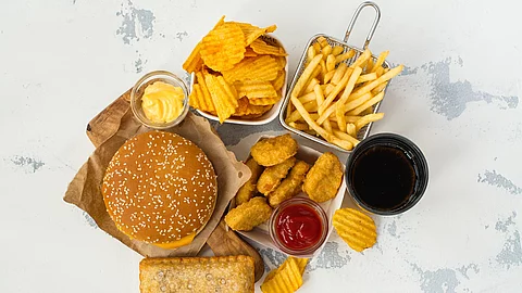Junk Food auf weißem Hintergrund: Chips, Nuggets, Burger, Pommes frites