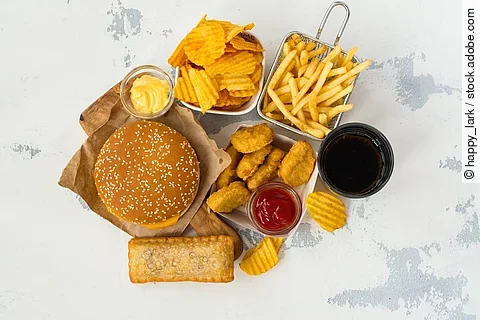 Junk Food auf weißem Hintergrund: Chips, Nuggets, Burger, Pommes frites