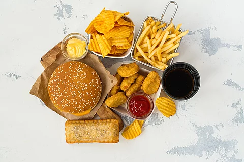 Junk Food auf weißem Hintergrund: Chips, Nuggets, Burger, Pommes frites