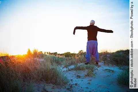 Frau mit Haarverlust hält Arme nach oben in der Natur