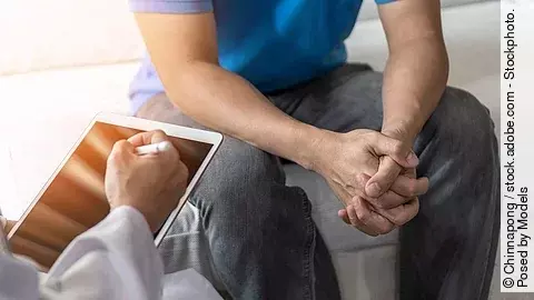 Mann sitzt auf Untersuchungsliege