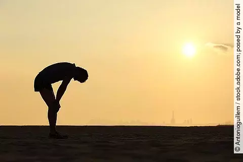 Silhouette eines erschöpften Menschen vor Sonnenuntergang
