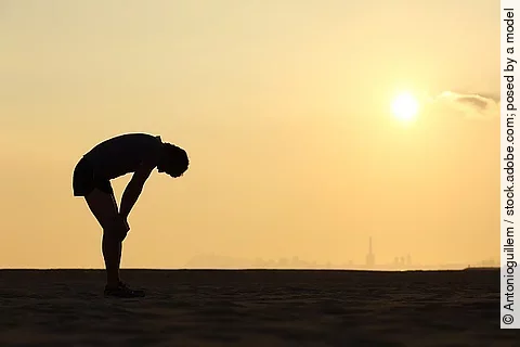 Silhouette eines erschöpften Menschen vor Sonnenuntergang