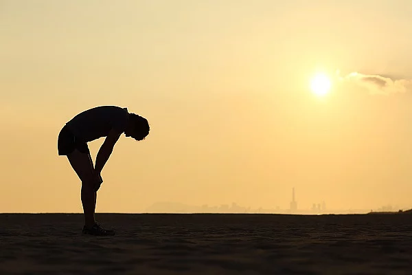 Silhouette eines erschöpften Menschen vor Sonnenuntergang