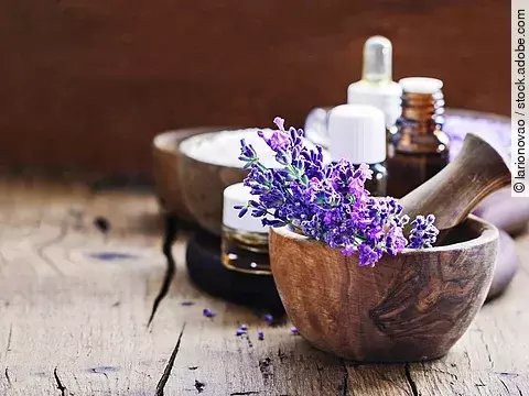 Lavendelblüten in Holzschale, Braunfläschchen mit ätherischem Öl