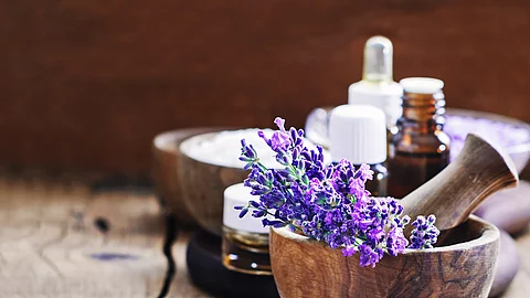 Lavendelblüten in Holzschale, Braunfläschchen mit ätherischem Öl