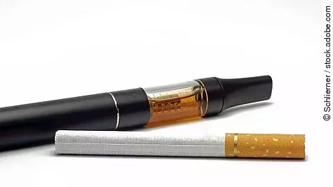 Herkömmliche Zigarette im Vordergrund, E-Zigarette im Hintergrund.