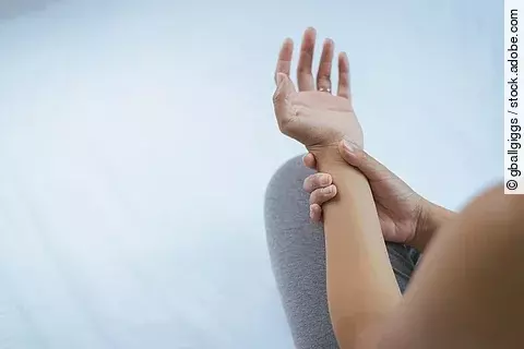 Frau hält ihren schmerzenden Arm fest. 