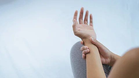 Frau hält ihren schmerzenden Arm fest. 