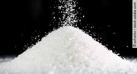 Ein Haufen Zucker auf schwarzem Hintergrund. 