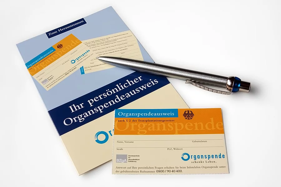 Flyer mit Organspendeausweis auf dem ein Kugelschreiber liegt.