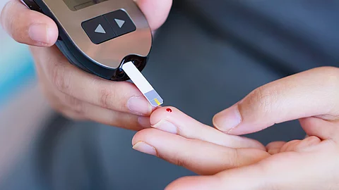 Mann testet seinen Blutzucker mit einem Teststreifen und Tropfen Blut am Finger