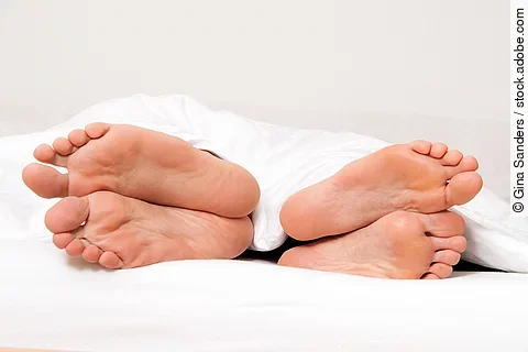 Dier Füße eines Paares im Bett. 