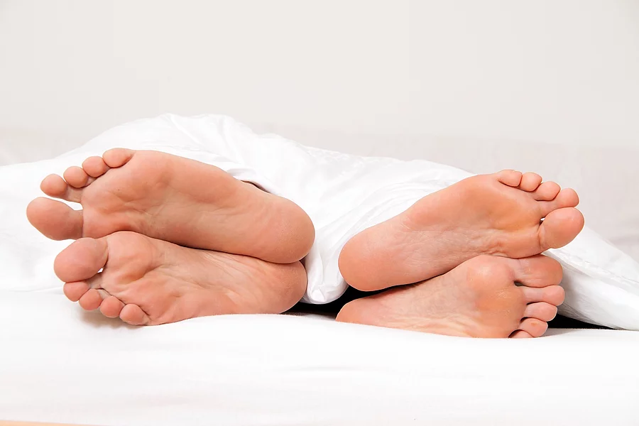 Dier Füße eines Paares im Bett. 