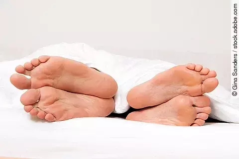 Dier Füße eines Paares im Bett. 